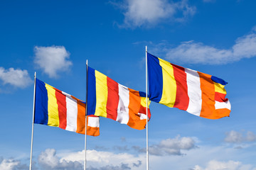 Waving colorful Buddhist Flags in cloudy blue sky background 