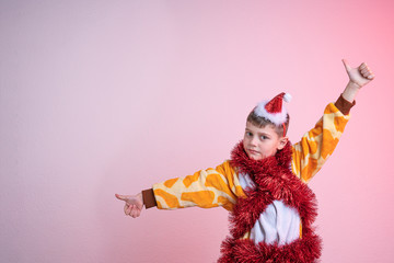 Calmy child, boy in red santa hat dressed in giraffe pajamas and wrapped in red new year's rain,...