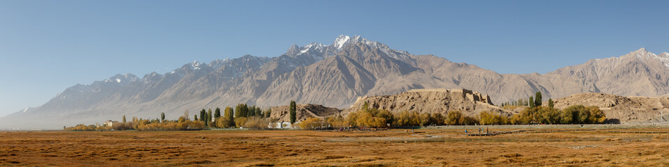 TASHGURKAN, XINJIANG / CHINA - October 3, 2017: Magnificent panorama of mountain range and ancient stone fort ruins. Tashgurkan is a town located near the Khunjerab Pass. Along the Karakorum Highway.