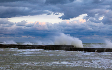 blue stormy clouds, storm at sea, waves are breaking of the pier, dirty orange water