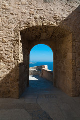 Fototapeta na wymiar View to the sea through a medieval castle archway