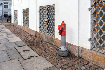 Fire hydrant on the street, near the wall of the house