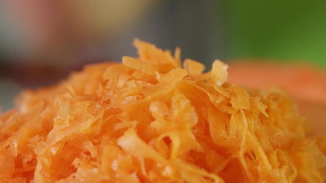 Grated fresh carrot on wooden kitchen board, close up