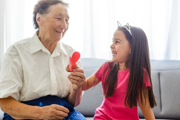 elderly grandmother and granddaughter hold a red heart