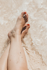 Fototapeta premium Bare feet in the surf on a white sand beach