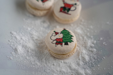 Obraz na płótnie Canvas White french macaroons with mouse and christmas tree print on white table. Minimal food bakery concept. Flat lay top view.