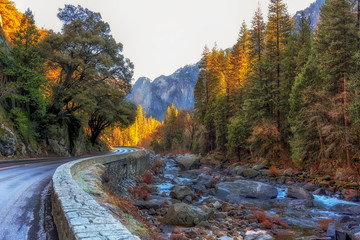 on the 140 road to yosemite beside the merced river in winter with sun highlighting some trees and...