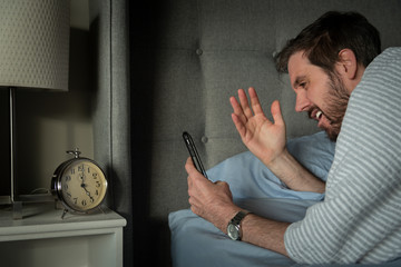 Man reacting to information on his smart phone while waking up in the morning.