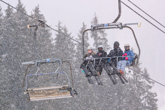 Winter landscape - view of the chairlift lift with skiers in the winter mountain forest during a snowfall