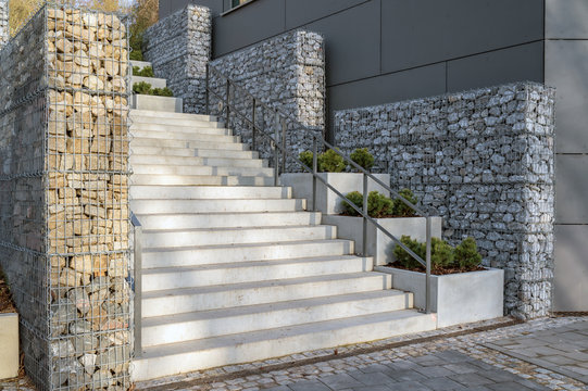 Moderne Treppe aus Beton mit Gabionenzaun als Blickfang