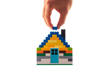 House made of classic building blocks, white studio background.