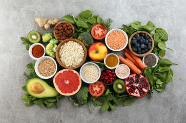 Healthy food clean eating selection: fruit, vegetable, seeds, superfood, cereals, leaf vegetable on rustic background