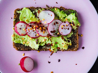 Dark rye bread toast with avocado, radishes and chili flakes