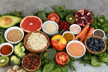 Healthy food clean eating selection: fruit, vegetable, seeds, superfood, cereals, leaf vegetable on rustic background