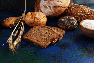 Assortment of baked bread and bread rolls and cutted bread on table background