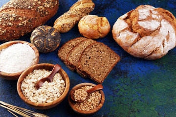 Assortment of baked bread and bread rolls and cutted bread on table background