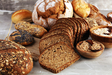 Assortment of baked bread and bread rolls and cutted bread on table background
