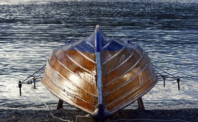Wooden rowing boat upturned at lakeside Windermere Lake District Engalnd