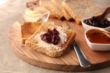 Toast bread with homemade strawberry jam and apricot marmalade on rustic table served with butter...