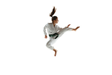 Fototapeta na wymiar Confident junior in kimono practicing hand-to-hand combat, martial arts. Young female mongol fighter with green belt training on white studio background. Concept of healthy lifestyle, sport, action.