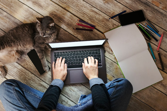woman with a cat sitting on floor and using laptop