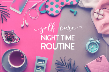 Text "Self care night time routine". Healthy night sleep creative concept. Sleeping mask, alarm clock, earphones, earplugs, tea and pills. Split neon two tone pink green background with palm leaves.