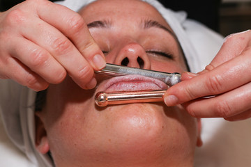 Fototapeta premium Close up side view of woman having beauty treatment in spa.Therapist applying jade roller on lips.
