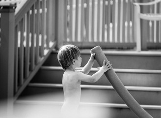 Toddler boy playing with a pool noodle