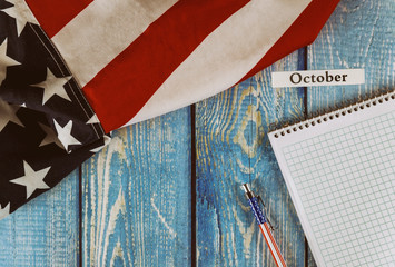 October month of calendar year United States of America flag of symbol of freedom and democracy with blank notepad and pen on office wooden table