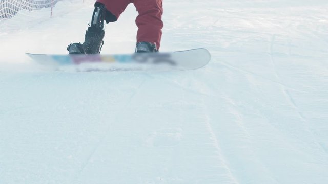Winter snowboarding - A man with modern prosthetic leg skating down the mountain and slows down in front of the camera