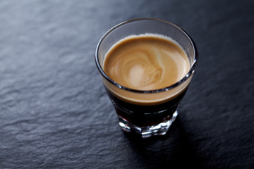 Coffee in glass cup on dark stone background. Close up. 