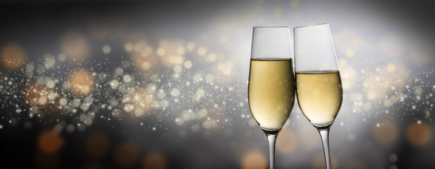 Happy New Year 2020, two champagne glass flutes toasting against a dark bubble bokeh background, party concept in panoramic format with copy space © Maren Winter