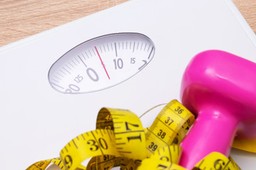 weight scale with tape measure and gym weights, concept of healthy life and exercise