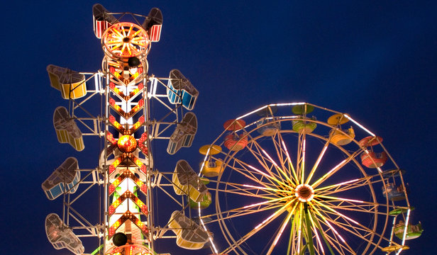 Neon Lighted Carnival Rides Against Dim Night Sky