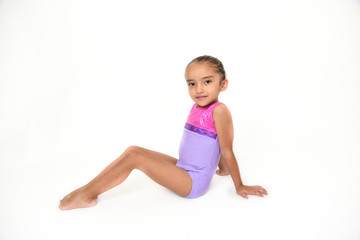 small latin girl doing gymnastics with white background and purple sportswear