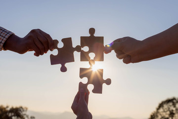 hands holding piece of blank jigsaw puzzle at sunset background