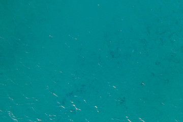 aerial view of the texture of the surface of turquoise water with sun reflections