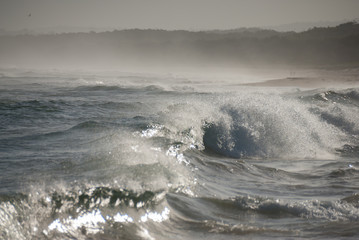 Surfing waves making mist in the late afternoon light at Lake Conjola, Australia