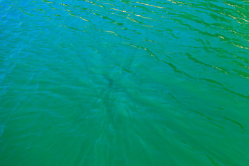 aerial view of the texture of the surface of turquoise water with sun reflections
