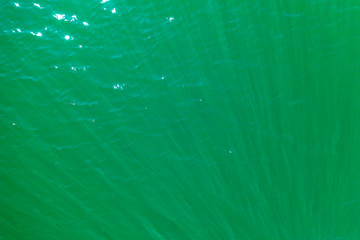 aerial view of the texture of the surface of turquoise water with sun reflections