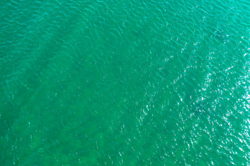 aerial view of the texture of the surface of turquoise water with sun reflections
