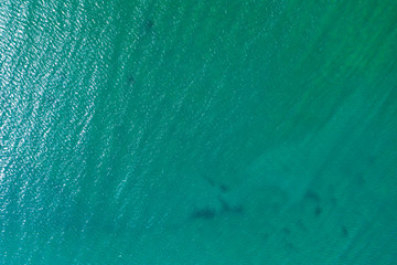 aerial view of the texture of the surface of turquoise water with sun reflections