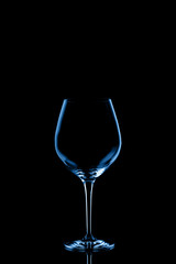 Red wine glass toned in classic blue on the dark background.. Fine cristal glassware concept. Vertical