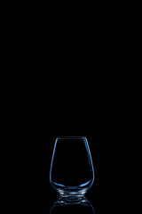 Modern water or wine glass toned in classic blue on the dark background.. Fine cristal glassware concept. Vertical