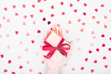 Craft box with red ribbon bow in female hand. Valentine day and eco-friendly wrapping concept. Trendy minimalistic flat lay design background. Horizontal