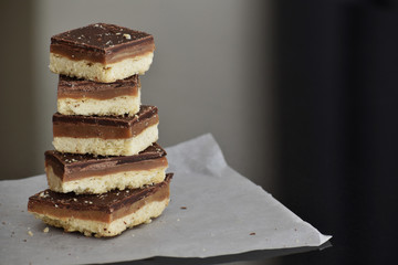 Millionaire's shortbread with chocolate and caramel. Copy space is on the right side. Selective...