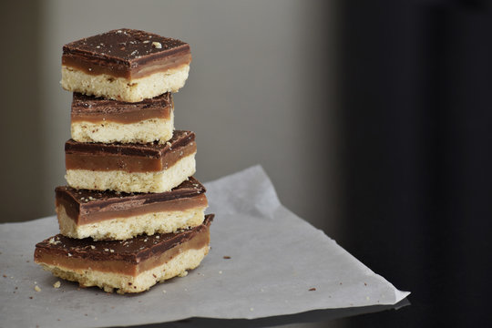 Millionaire's shortbread with chocolate and caramel. Copy space is on the right side. Selective focus.	