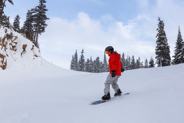 Male Snowboarder is riding down a ski run in wintertime. Taken on Whistler Mountain, British Columbia, Canada.