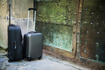 A couple of suitcases waiting in front of beautiful large rustic greenish metal castle doors for people who like adventure and enjoy lifestyle spooky hotel accommodations and country style traveling