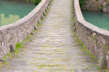 Obraz premium Bridge of a devil. Bridge over the river in Tuscany. Built in the 11 century. Ancient masonry covered with moss.